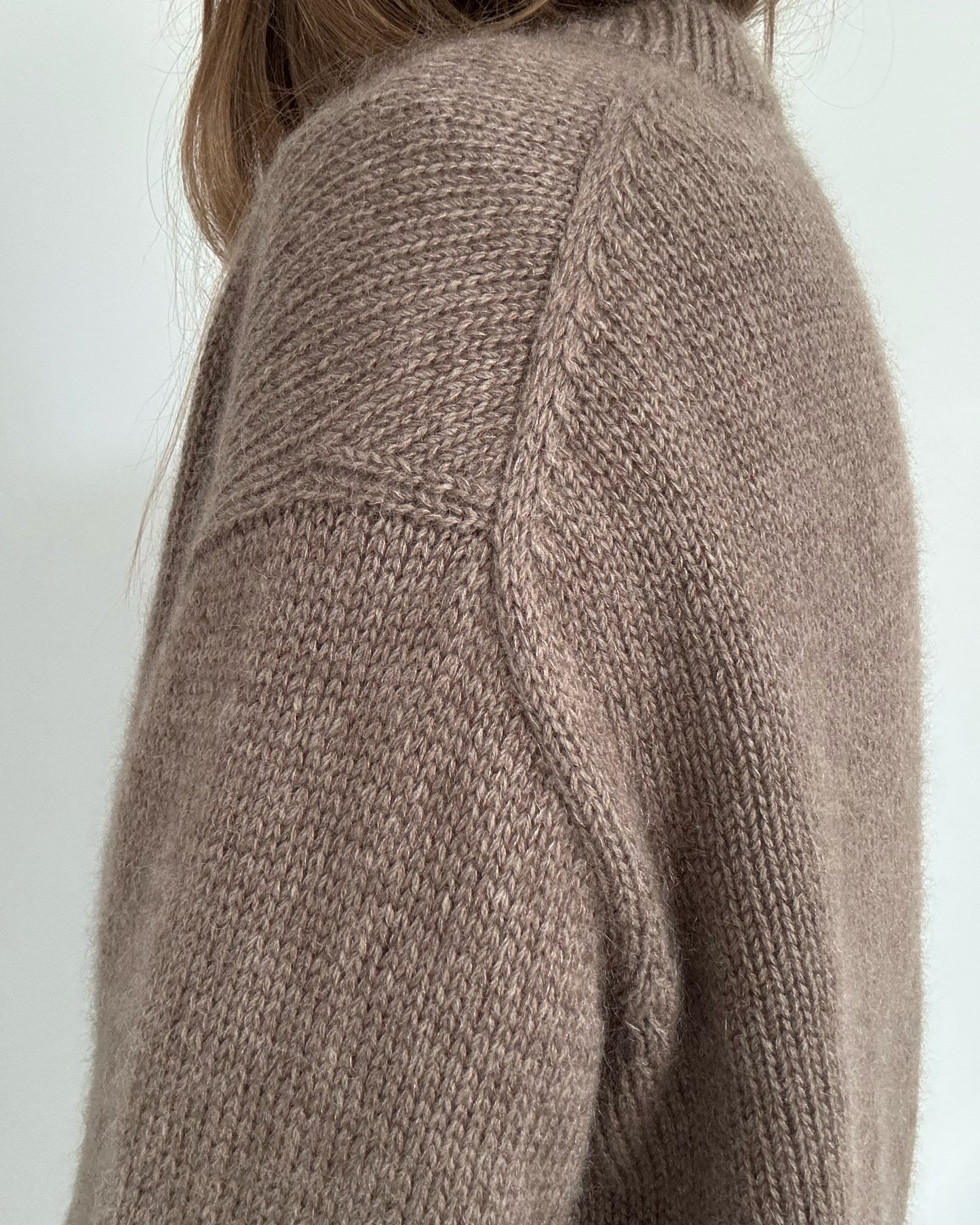 Hands in pockets image presents clean hem with double knitting rib and subtle slit shaping for movement.