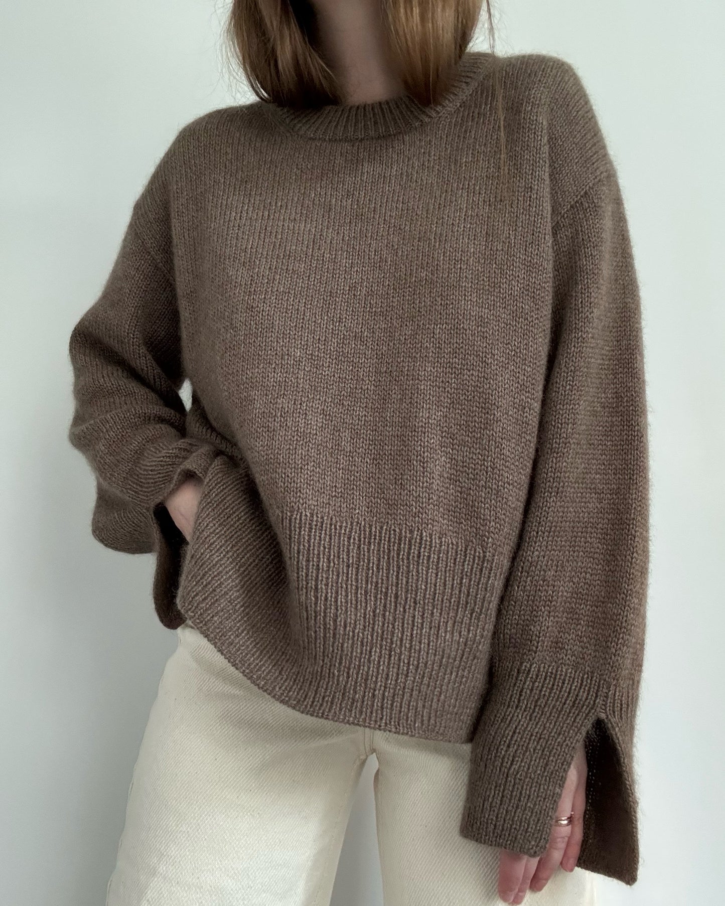 Walking shot captures flow of oversized pullover styled for ladies knitwear in contemporary Scandinavian mood.