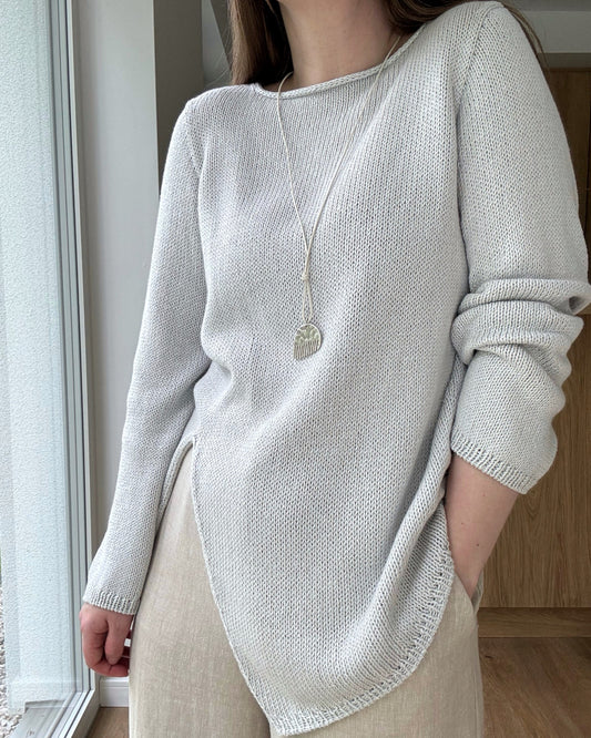 Liv Blouse ułożona na płasko pokazuje nowoczesny dekolt łódkowy i asymetryczną konstrukcję od góry w regularnym kroju z bawełny lnu jedwabiu.