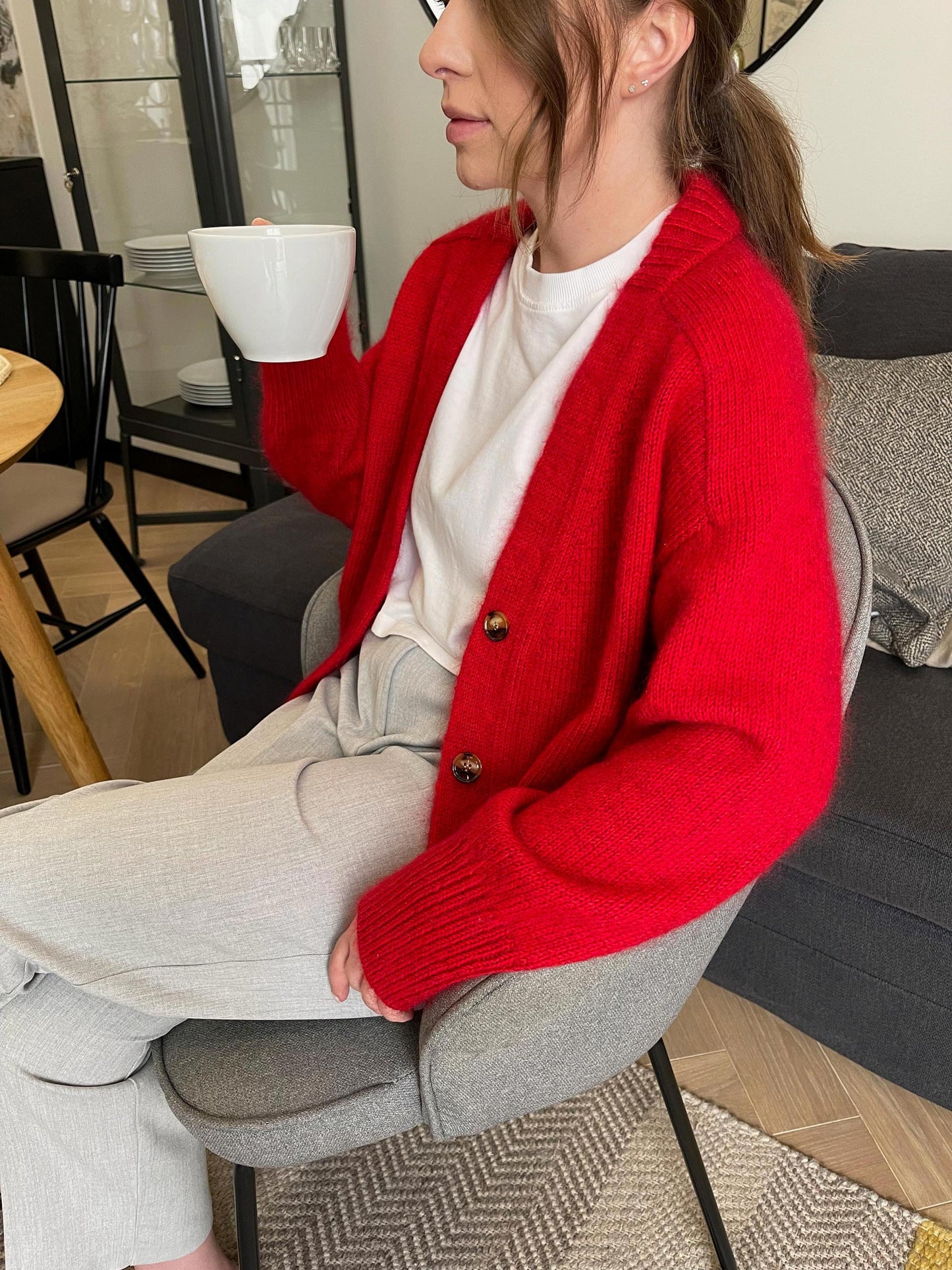 Kvinde graciøst fremviser den dybe V-hals funktion af Paul Cardigan, der fremhæver dens moderne elegance.