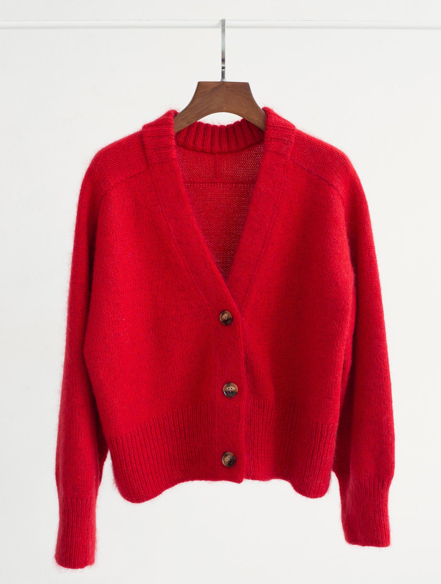 Woman gracefully showcasing the deep V-neck feature of the Paul Cardigan, highlighting its modern elegance.