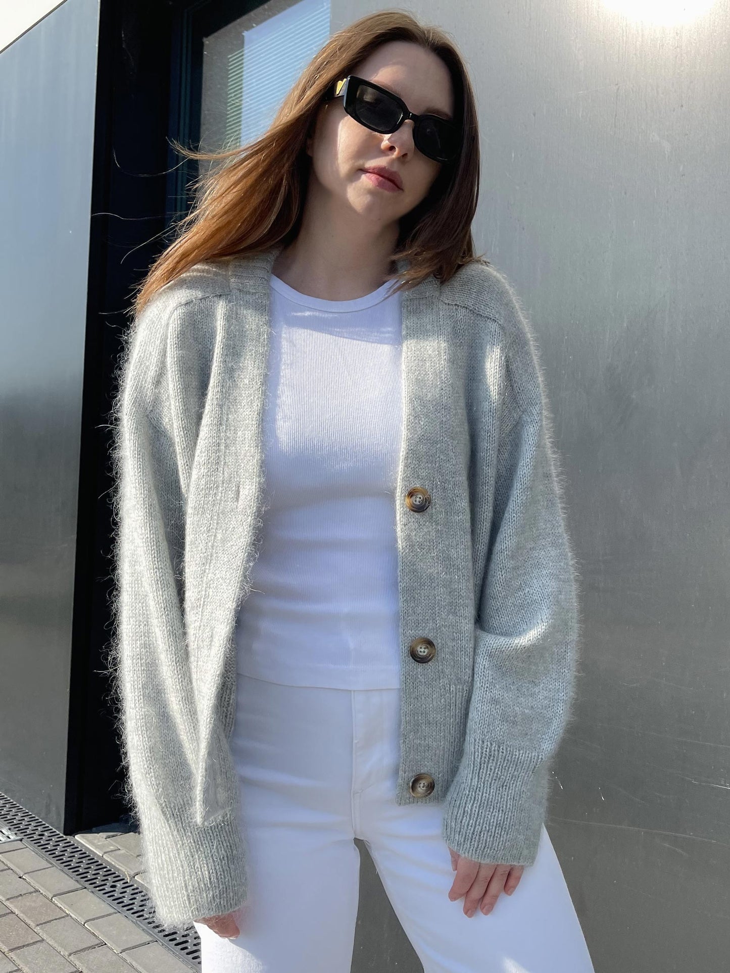 Completed Paul Cardigan draped over a chair, displaying its oversized fit and contemporary design, in a soft gray hue