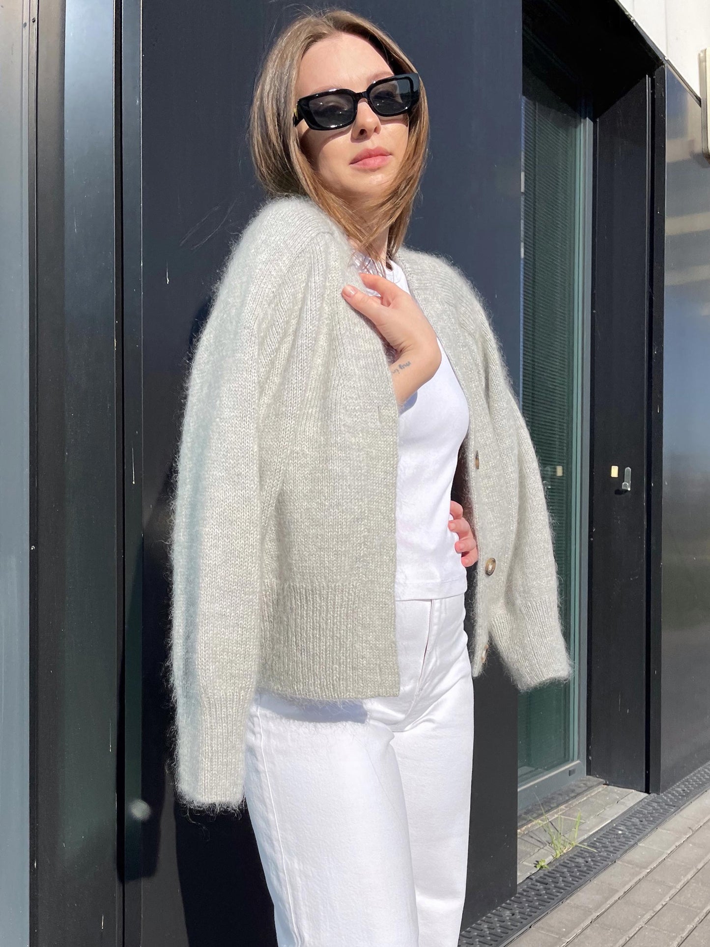 Completed Paul Cardigan draped over a chair, displaying its oversized fit and contemporary design, in a soft gray hue