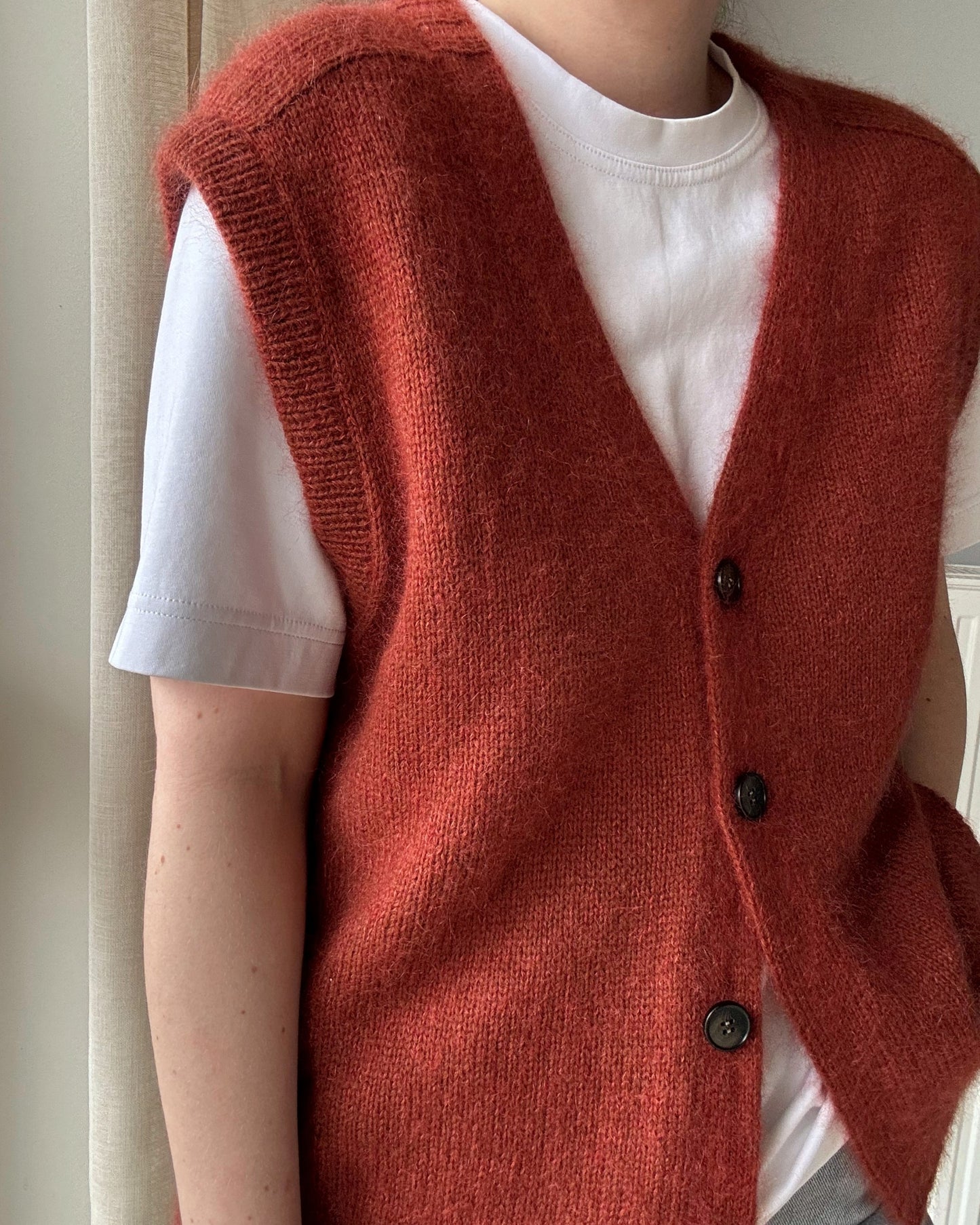 Paul Vest fortgeschrittenes Strickmuster, das einen ärmellosen Cardigan mit Knopfverschluss und Top-Down-Technik zeigt.