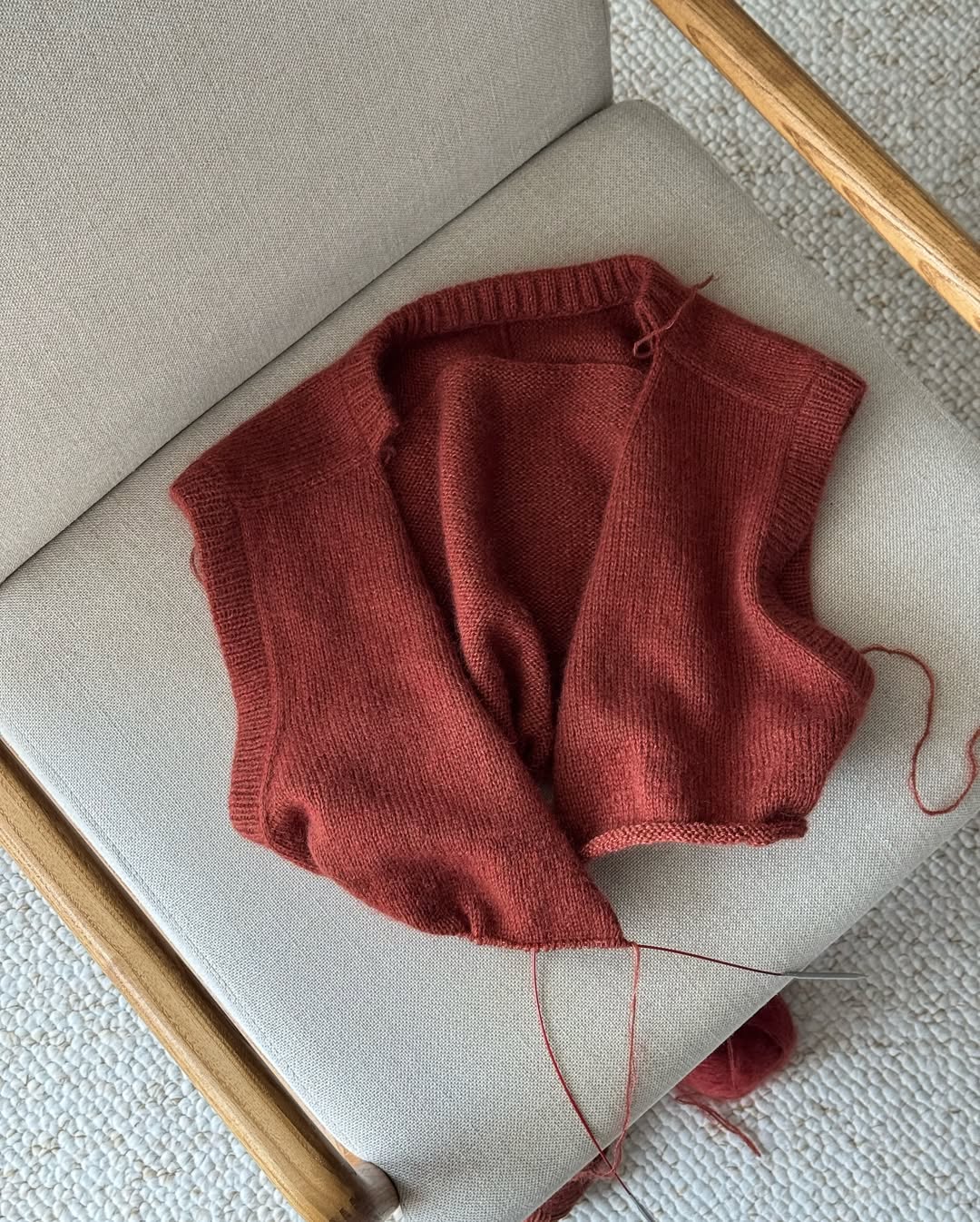 Fortgeschrittenes Muster für einen ärmellosen Cardigan, der klassisches Design mit weichen, glatt rechten Strickdetails kombiniert.