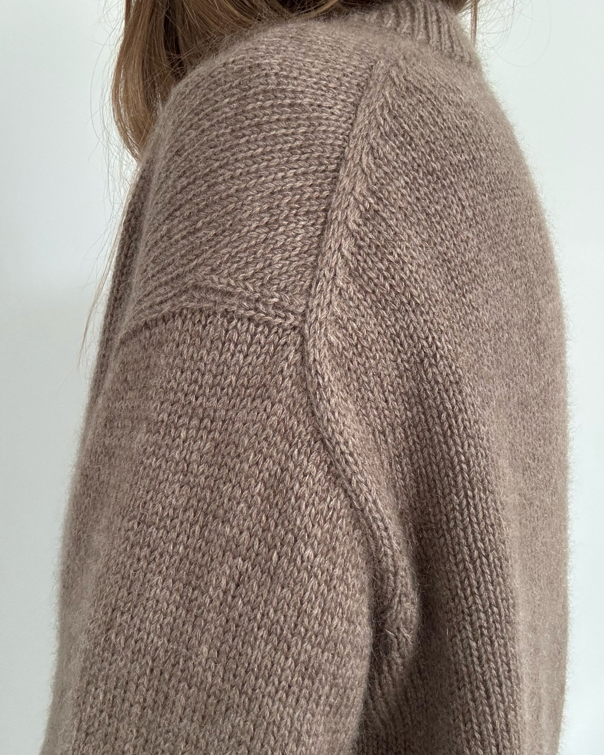 Hands in pockets image presents clean hem with double knitting rib and subtle slit shaping for movement.