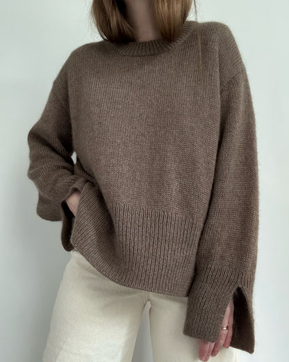 Walking shot captures flow of oversized pullover styled for ladies knitwear in contemporary Scandinavian mood.