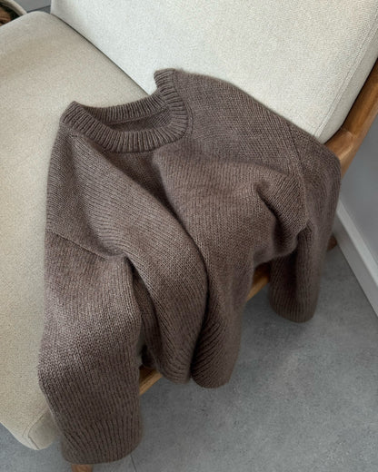 Rozluźniona poza pokazuje luźny krój i rozcięcia boczne klasycznego swetra gładkim ściegiem z Przewodnika Knit.