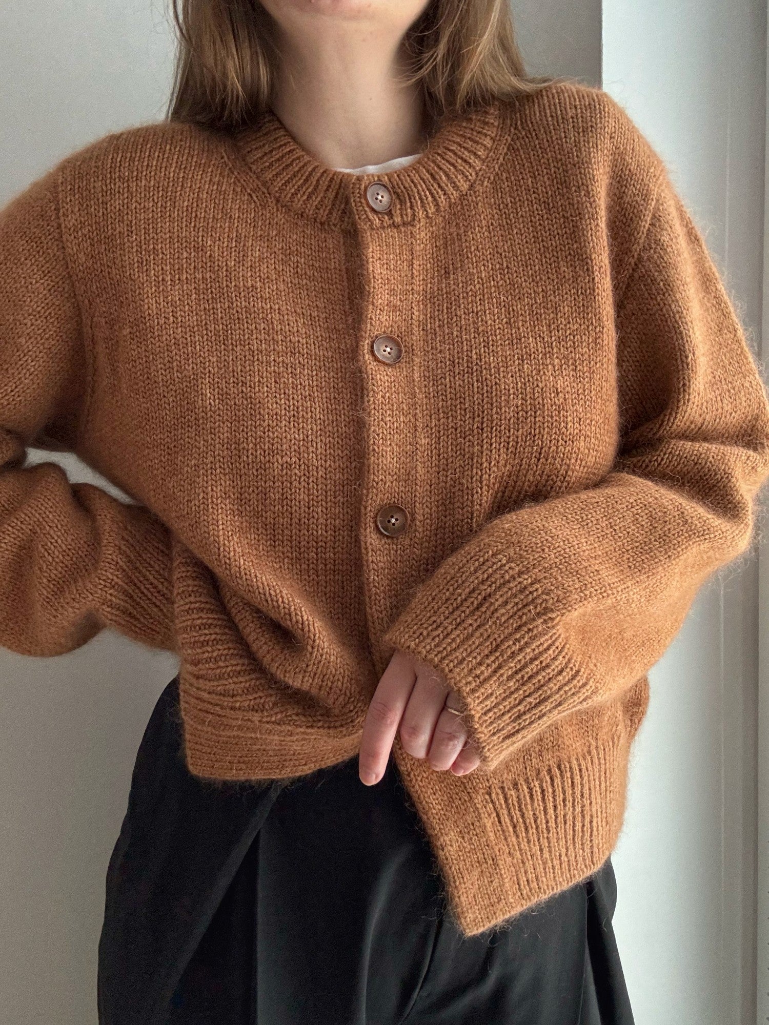 Cardigan med rund hals og droppede skuldre, top down i glatstrik, moderne og basic æstetik.