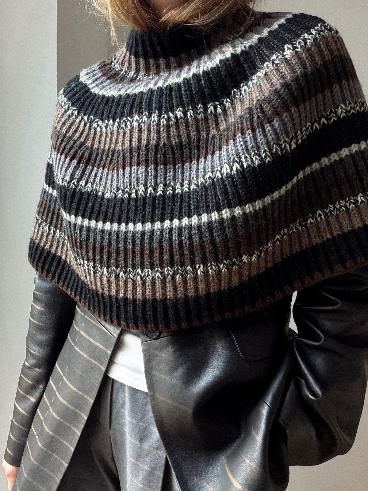 Side view of the capelet showing its short cape silhouette and softly flared lower edge.