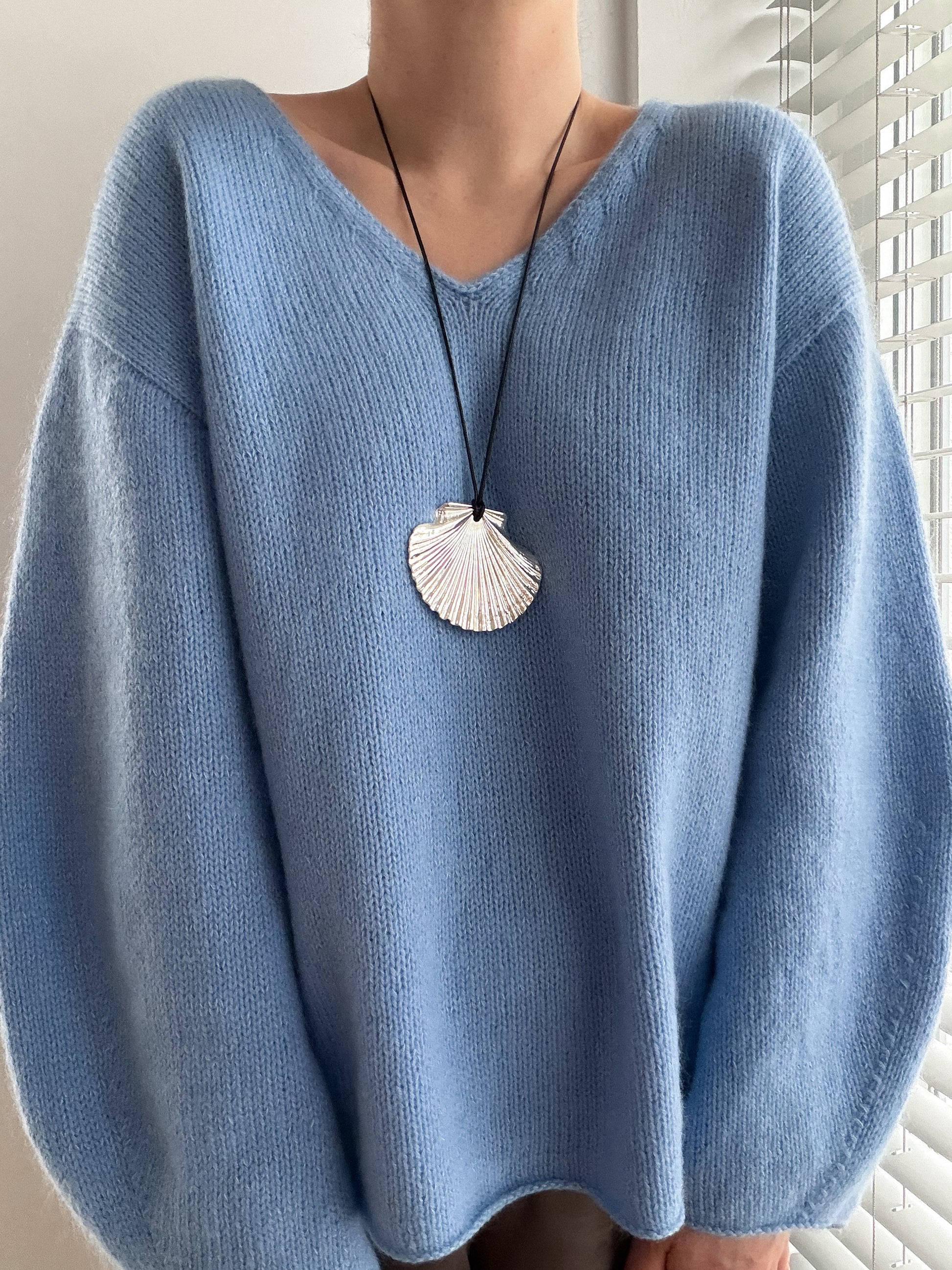 Vue de côté du Phoenix Sweater, pull à col en V profond avec une silhouette oversize élégante