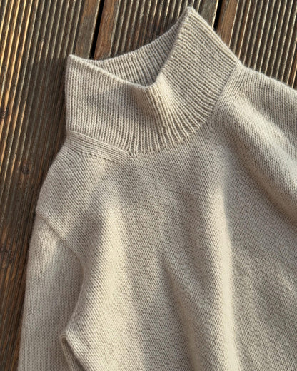 En mock neck-genser strikket ovenfra og ned, med raffinert glattstrikk for et minimalistisk uttrykk.