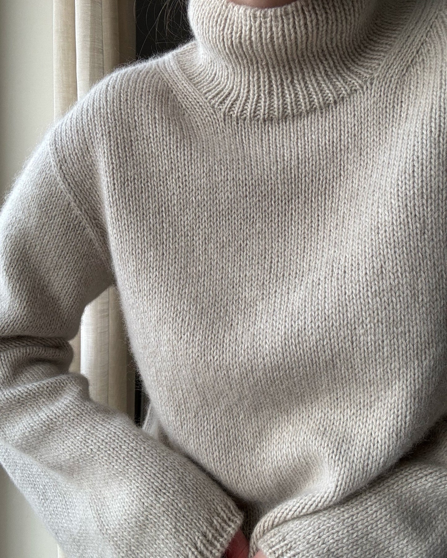 Turtleneck collar detail capturing the minimalistic style in alpaca wool.