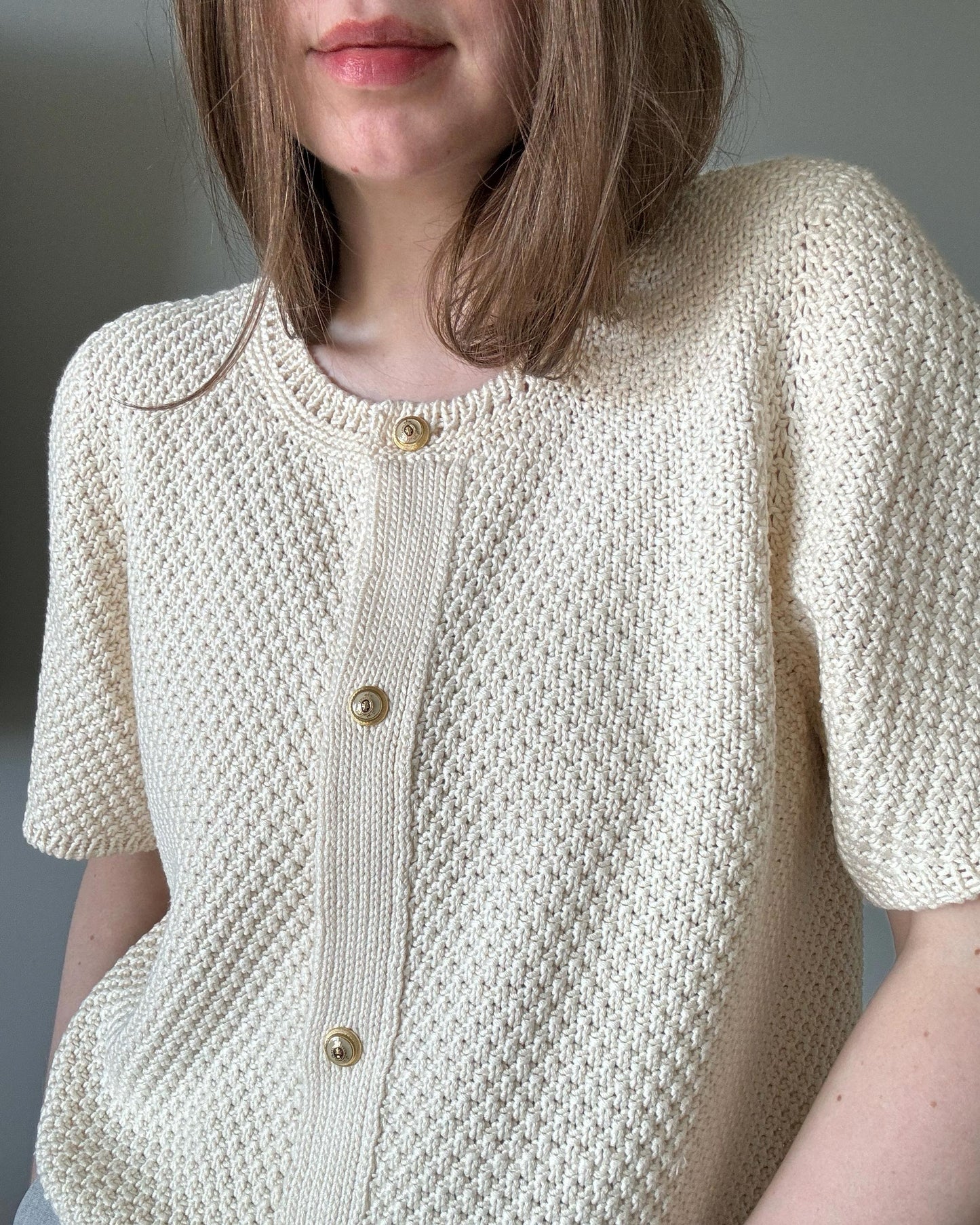 Weißer Manon-Cardigan, sommerlich gestrickt mit kurzen Ärmeln und Rundhalsausschnitt von moreca knit.