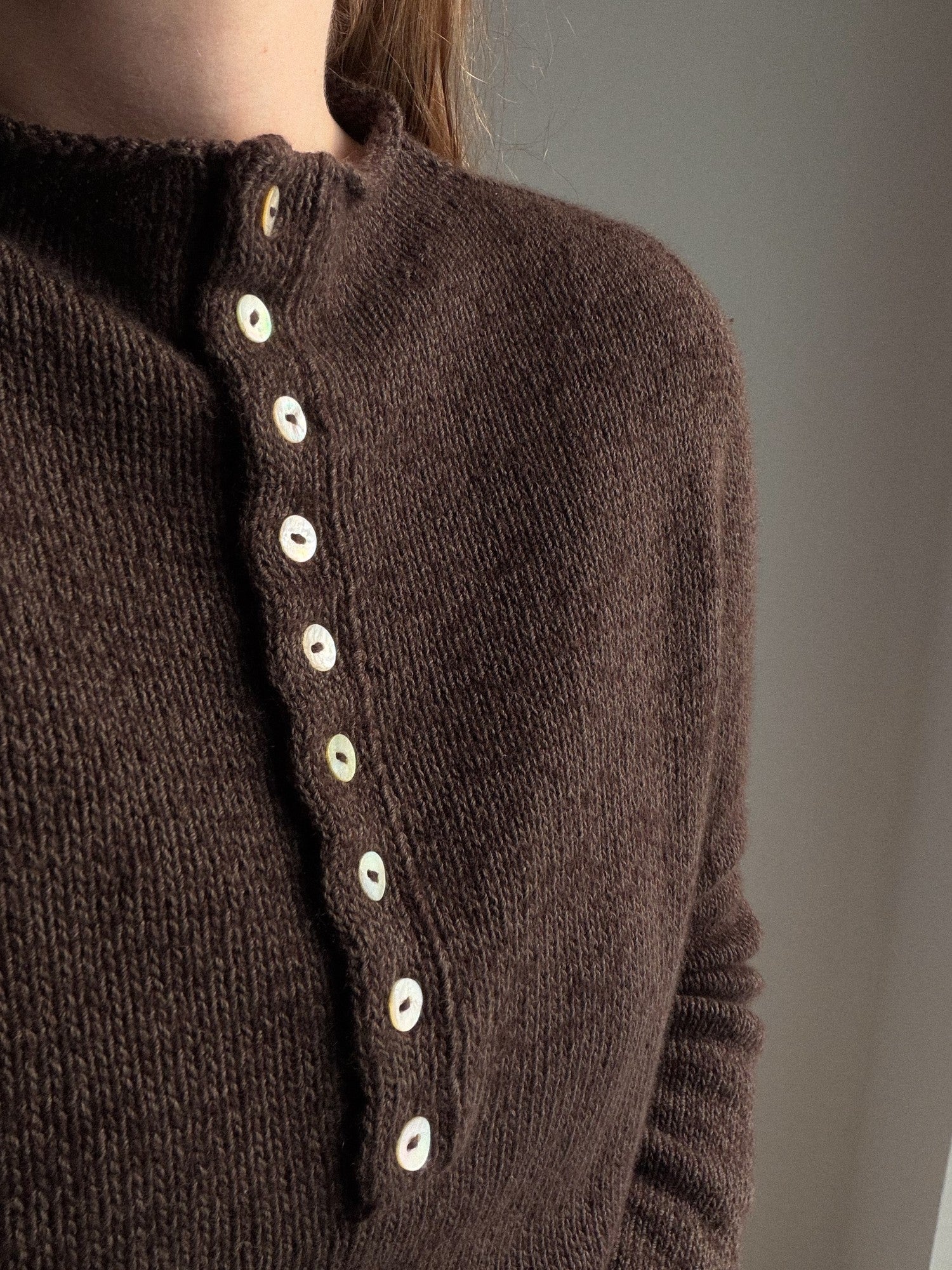 Mia Blouse 버튼업 스웨터의 측면 모습으로 부드러운 실루엣과 세련된 미니멀 디자인을 보여 줍니다.