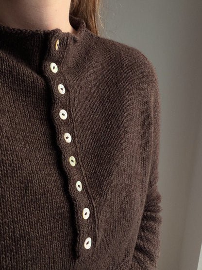 Mia Blouse 버튼업 스웨터의 측면 모습으로 부드러운 실루엣과 세련된 미니멀 디자인을 보여 줍니다.