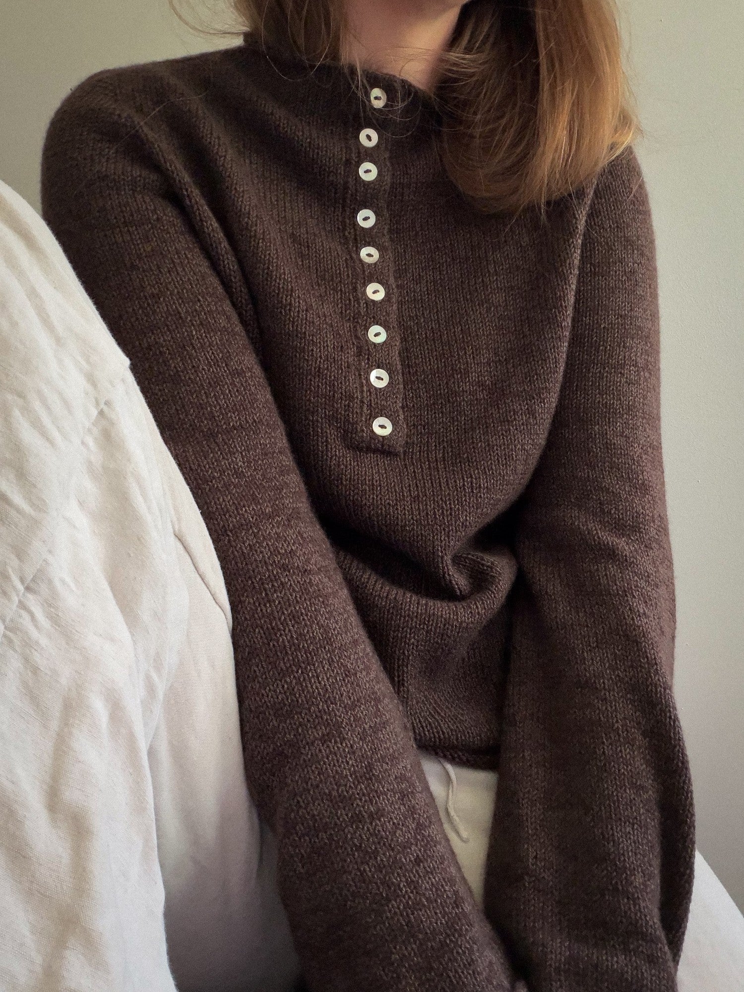 Pulower Mia Blouse pokazany w swobodnej pozie, z konstrukcją od góry i miękką minimalistyczną estetyką.