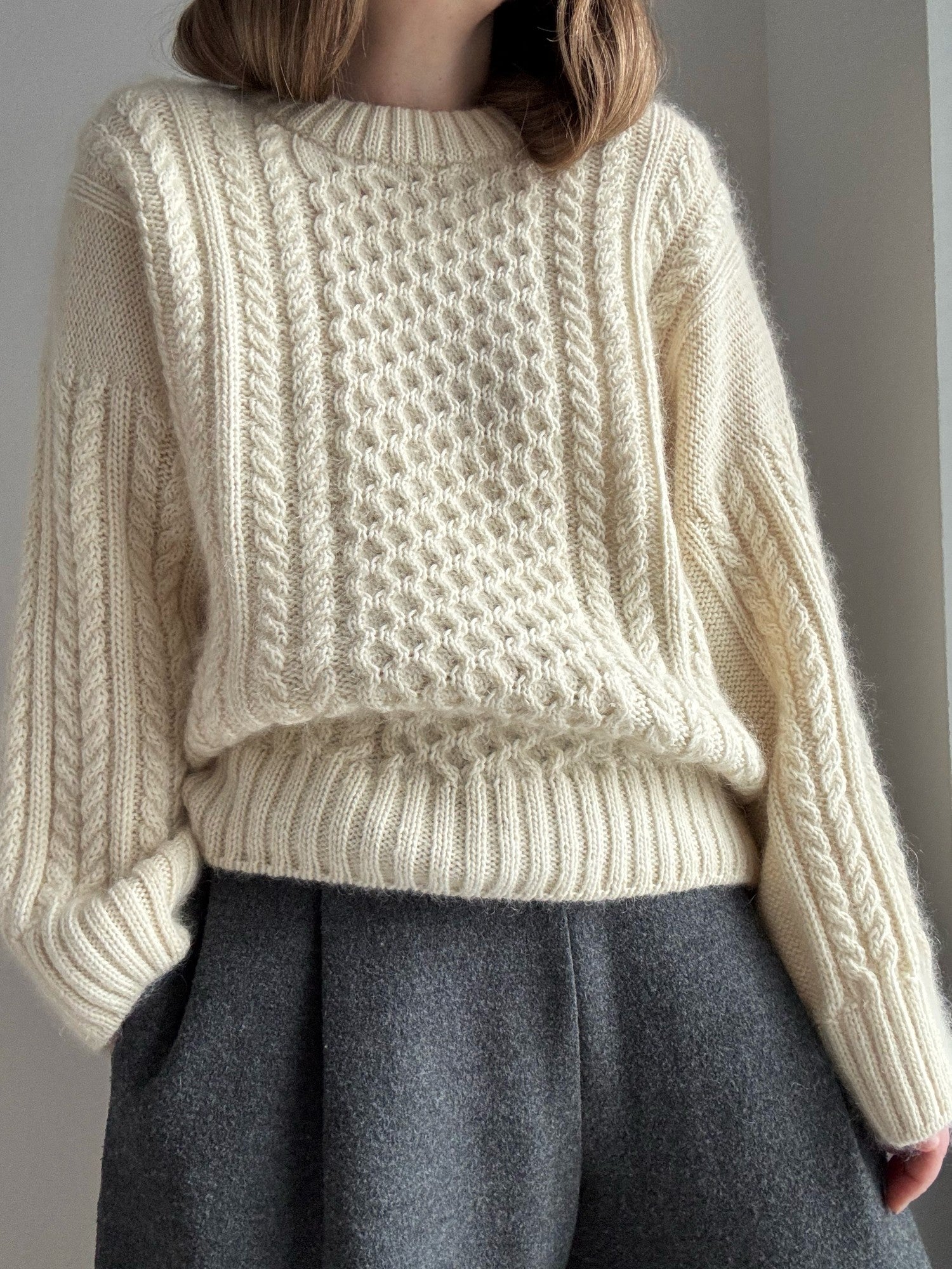 Ninon Sweater cable knitting pattern worn by designer showing oversized fit and textured cable structure