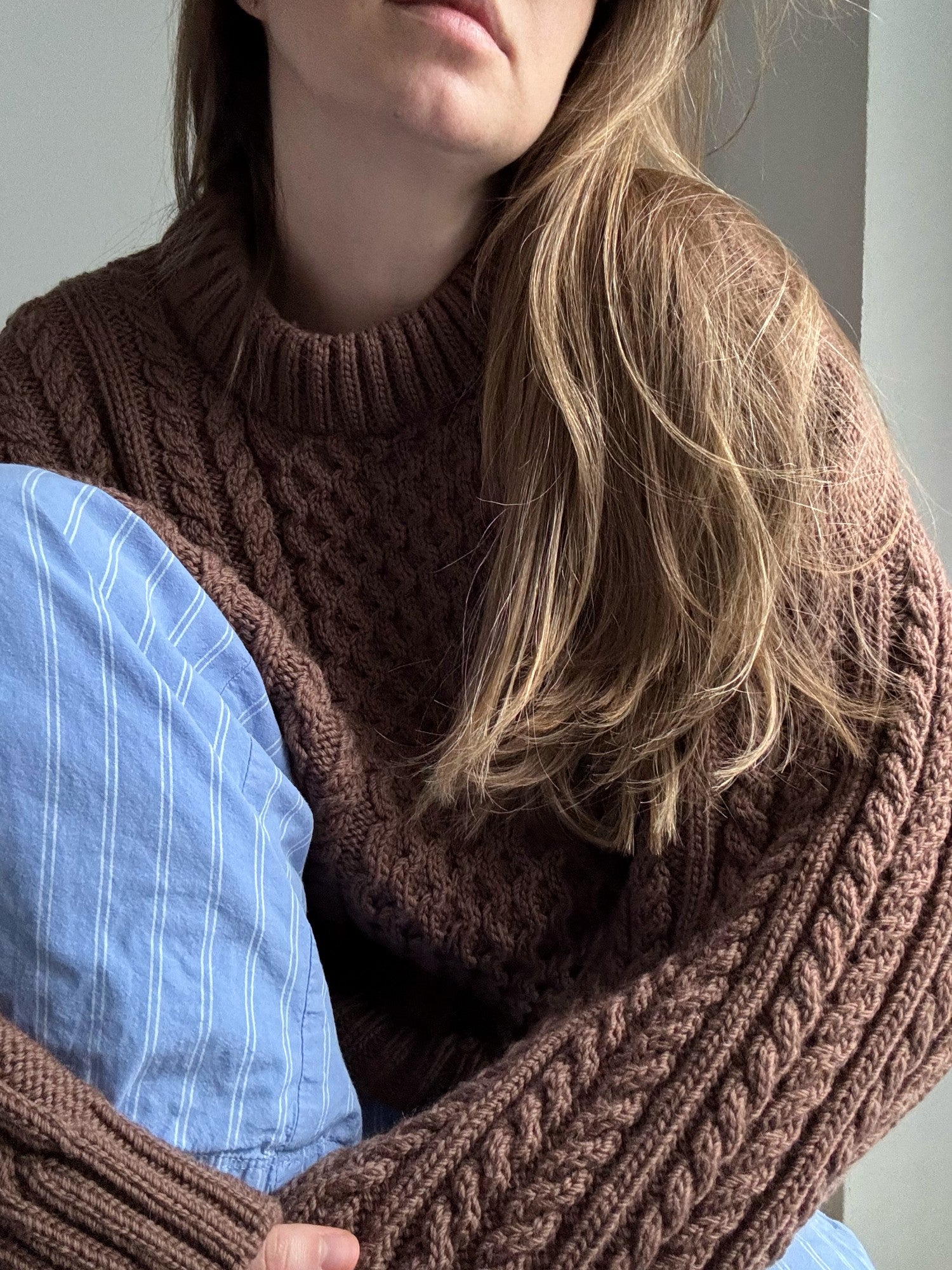 Womens cable sweater knitting pattern with drop shoulders and long sleeves photographed on model