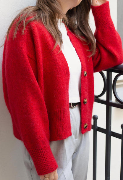 Close-up of the button-up front of the Paul Cardigan in red, illustrating the pattern's refined design.